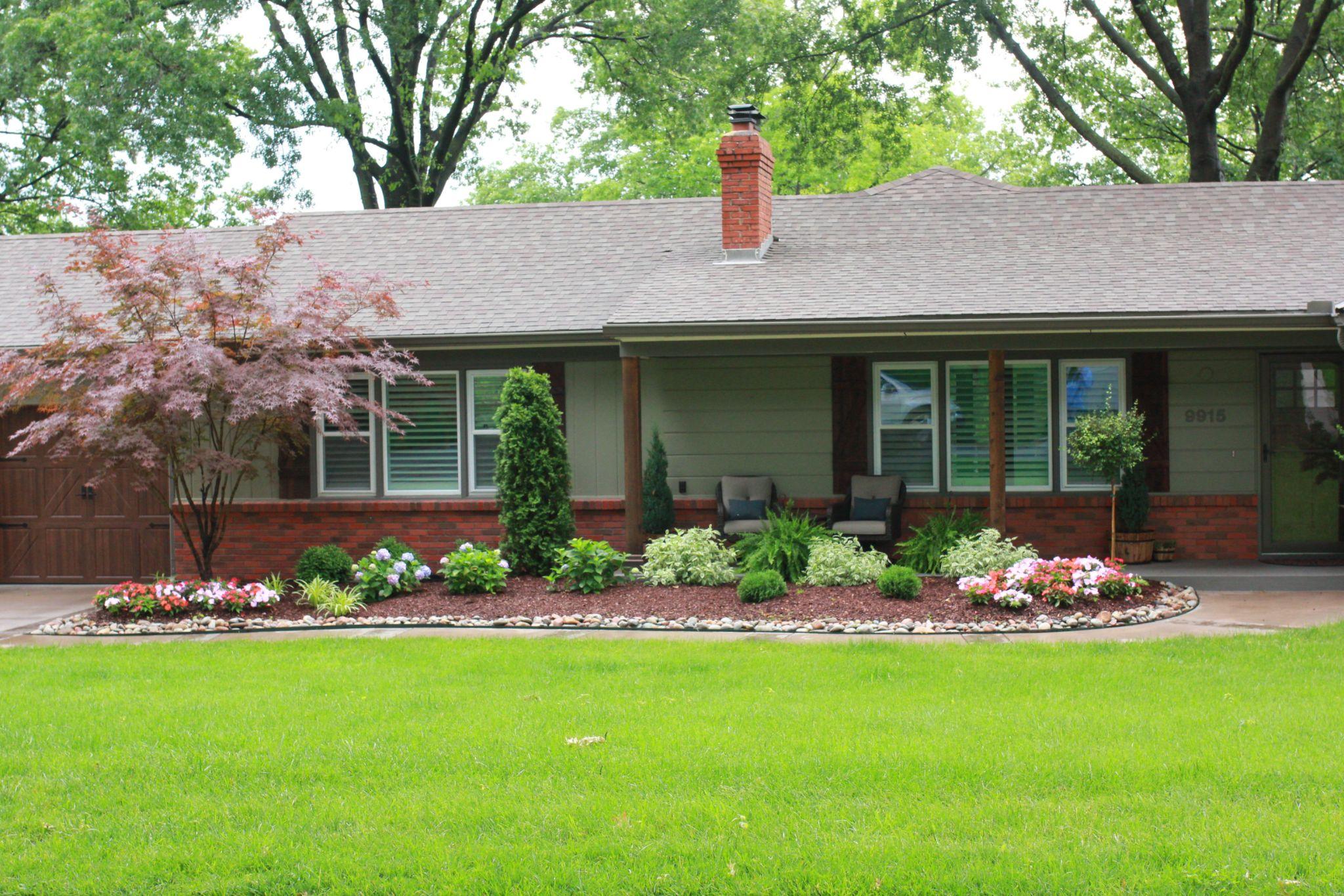 Front yard with colorful flower bed and brick home