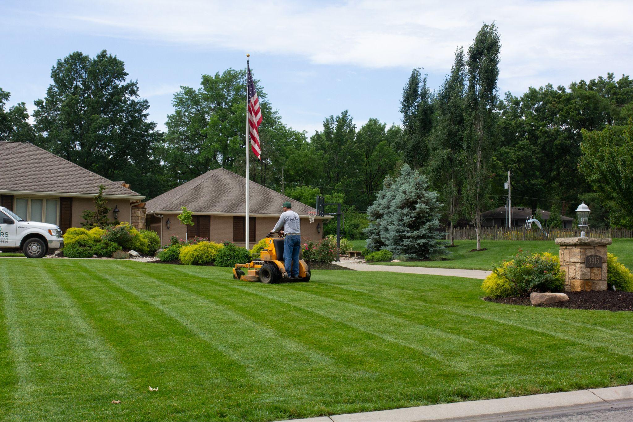 Professional lawn mowing service on a large residential property with striped turf and landscaped beds