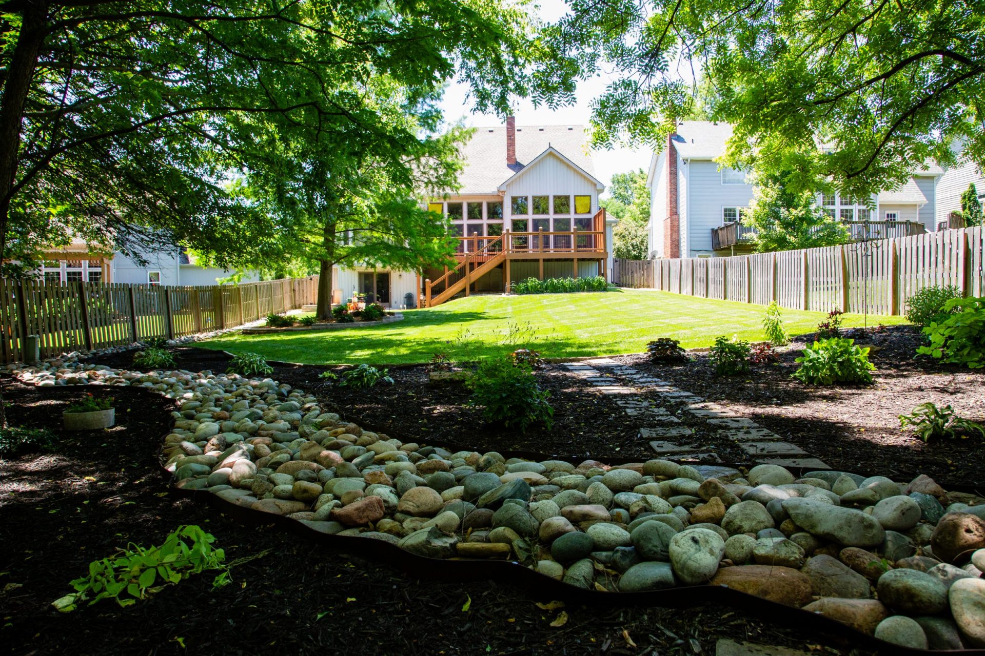 Well-manicured backyard of a suburban residence, featuring a mix of functional lawn space and decorative landscaping elements.